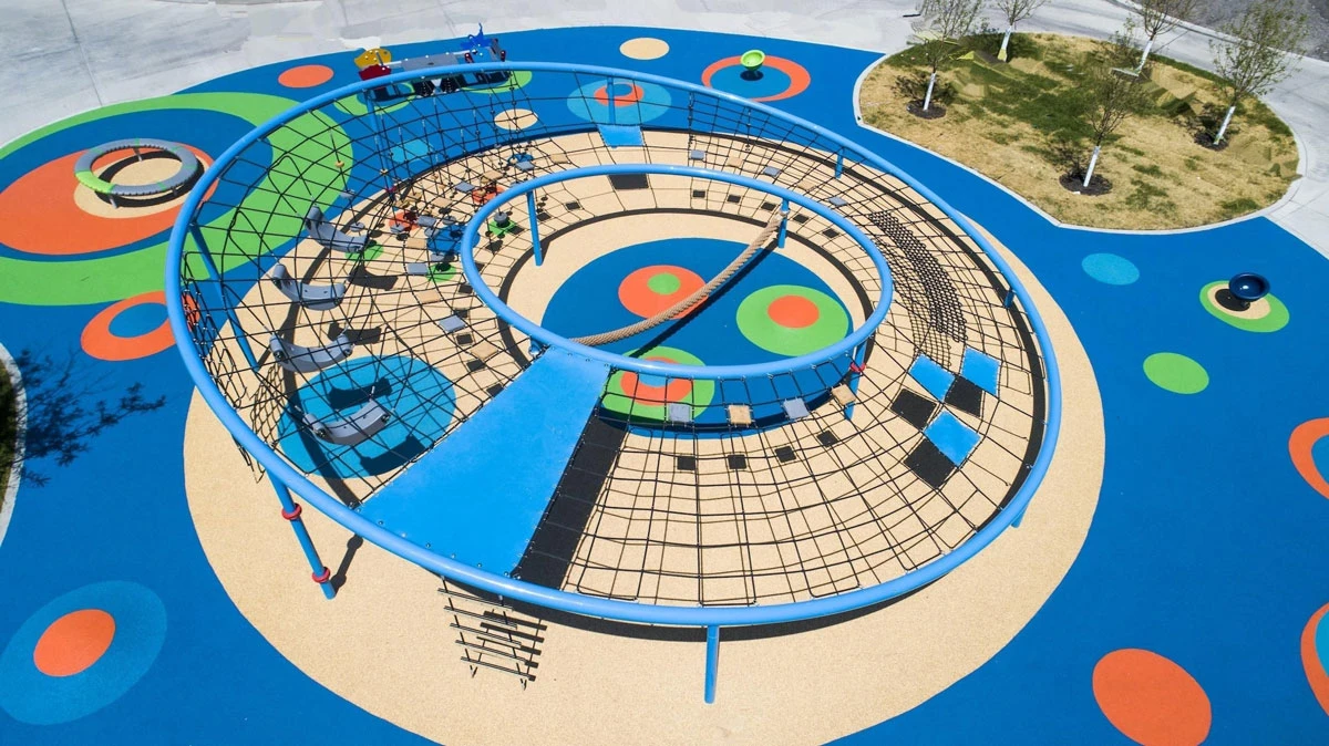 Residential playground design themed by circle and blue color, this playground has circles everywhere, the round rope net climbing equipment, the round balance beam, round rotating chair as well as the circle patterns on the EPDM flooring.